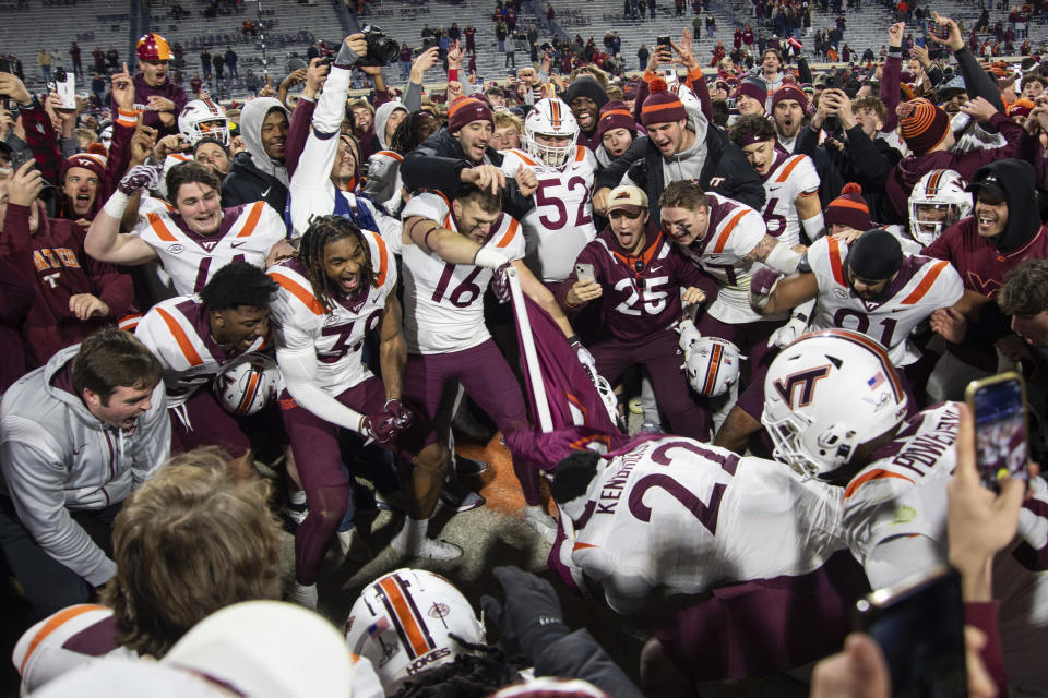 Virginia Tech players celebrate as defensive lineman Mario Kendricks (22) plants the Hokies flag on the 50-yard line after defeating Virginia in an NCAA college football game Saturday, Nov. 25, 2023, in Charlottesville, Va. (AP Photo/Mike Caudill)