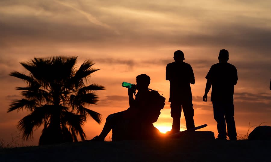 People view the sun set as a child drinks from a water bottle on June 15, 2021 in Los Angeles, temperatures soar in an early-season heatwave. (Frederic J. BROWN / AFP via Getty Images)