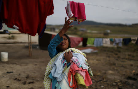 A Venezuelan indigenous girl of Pemon tribe picks her clothes up in the Brazilian indigenous village Tarau Paru in the border city of Pacaraima, Brazil April 12, 2019. Picture taken April 12. REUTERS/Pilar Olivares