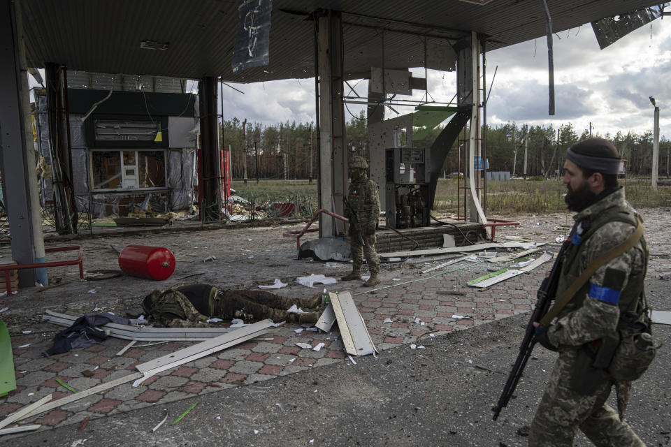 Soldados ucranianos encuentran el cadáver de un camarada caído en una gasolinera destruida en la ciudad recientemente recapturada de Lyman, en Ucrania, el lunes 3 de octubre de 2022. (AP Foto/Evgeniy Maloletka)