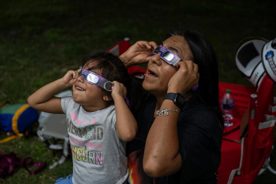 Rosalina Galdamez, 3, and her grandmother Erika Flores, of Houston, look up at the sun as the moon begins to pass between it and the sun Monday, April 8, 2024 at Zilker Park in Austin.