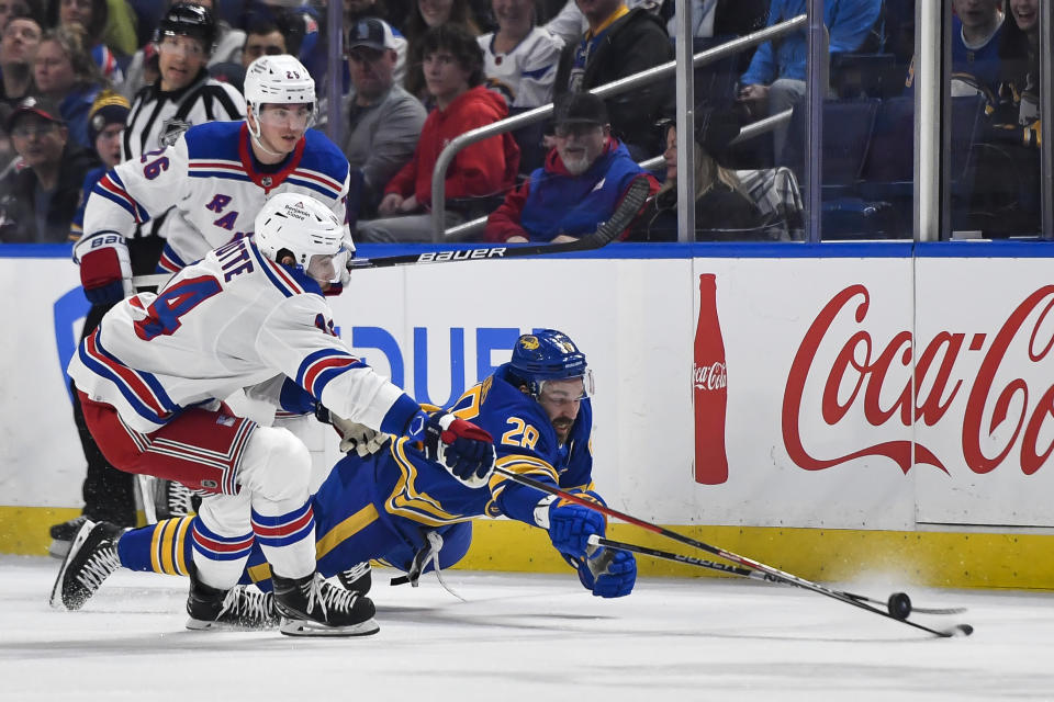Buffalo Sabres left wing Zemgus Girgensons, right, dives to poke the puck away from New York Rangers center Tyler Motte during the first period of an NHL hockey game in Buffalo, N.Y., Friday, March 31, 2023. (AP Photo/Adrian Kraus)