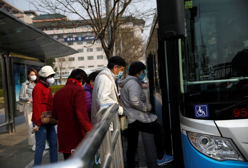 People wearing face masks board a bus on a street following an outbreak of the coronavirus disease (COVID-19), in Beijing