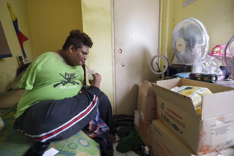 Mohamad Nor Abdullah, born without arms, drinks near donated goods in his rented room in Kuala Lumpur, Malaysia on July 3, 2021. When Mohamad Nor put a white flag outside his window late at night, he didn’t expect the swift outpouring of support. By morning, dozens of strangers knocked on his door, offering food, cash and encouragement. (AP Photo/Vincent Thian)