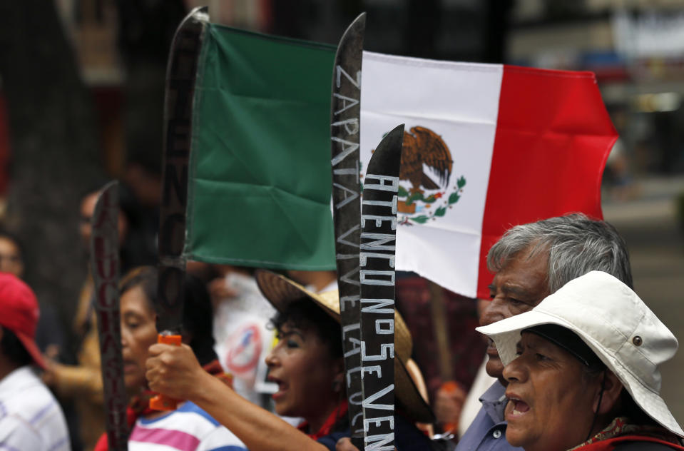 Residents who live in Atenco hold up machetes during a march against the construction of a new airport near their community, in Mexico City, Thursday, Aug. 23, 2018. Demonstrators marched through Mexico City Wednesday to protest a $15.7-billion airport project that threatens a decades-old effort to restore lakes that originally covered the valley. (AP Photo/Marco Ugarte)