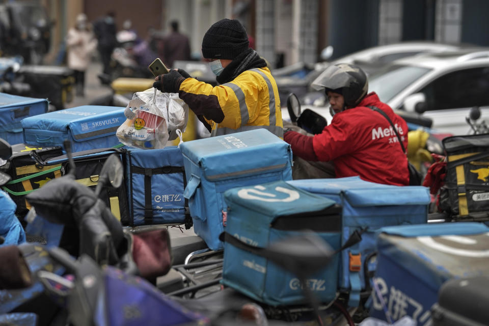 A food delivery worker wearing a face mask to help curb the spread of the coronavirus prepares to deliver foods for his customers outside a restaurant in Beijing on Thursday, Jan. 14, 2021. The e-commerce workers and delivery people who kept China fed during the pandemic, making their billionaire bosses even richer, are so unhappy with their pay and treatment that one just set himself on fire in protest. (AP Photo/Andy Wong)