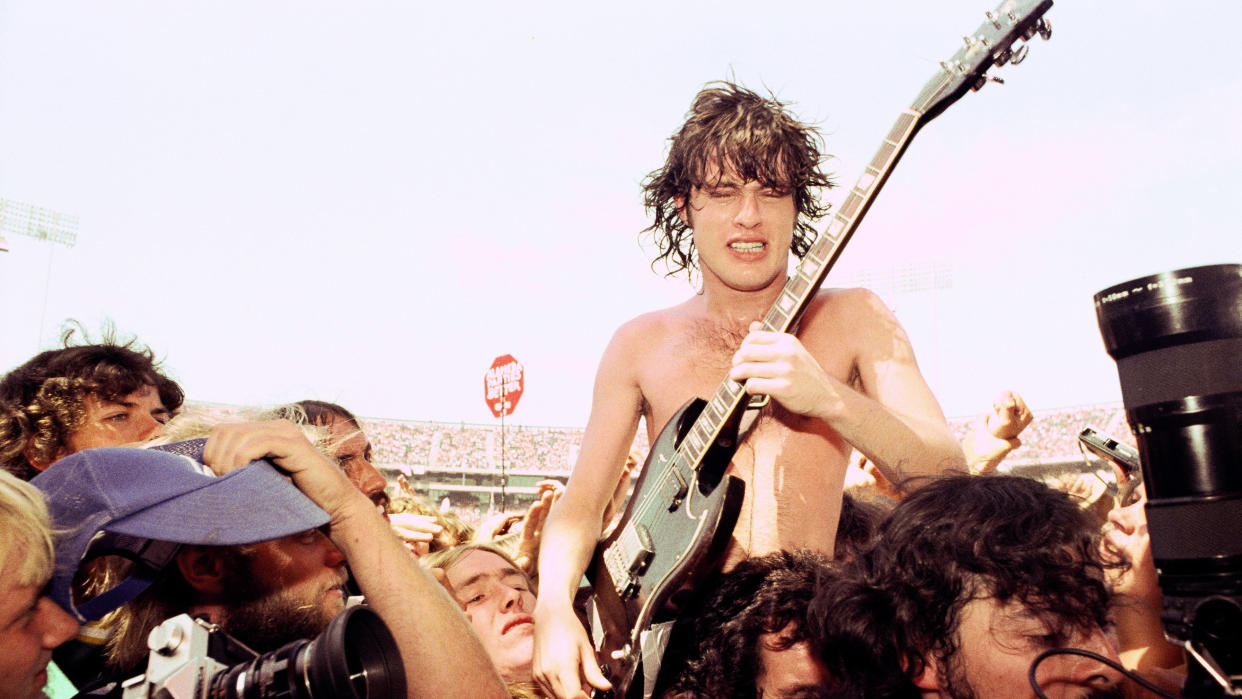  OAKLAND - 1978: L-R Angus Young and Bon Scott of AC/DC get swept away by fans and media at The Oakland Coliseum 1978 in Oakland, California. 