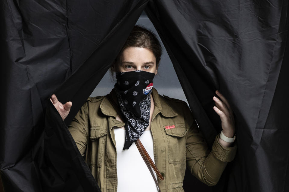 Jenn McCullough, que se cubre la boca con un pañuelo para protegerse del coronavirus, sale de una cabina de votación tras depositar su boleta en las primarias de Pennsylvania, en el Kimmel Center, Filadelfia, el 2 de junio de 2020. (AP Foto/Matt Rourke)