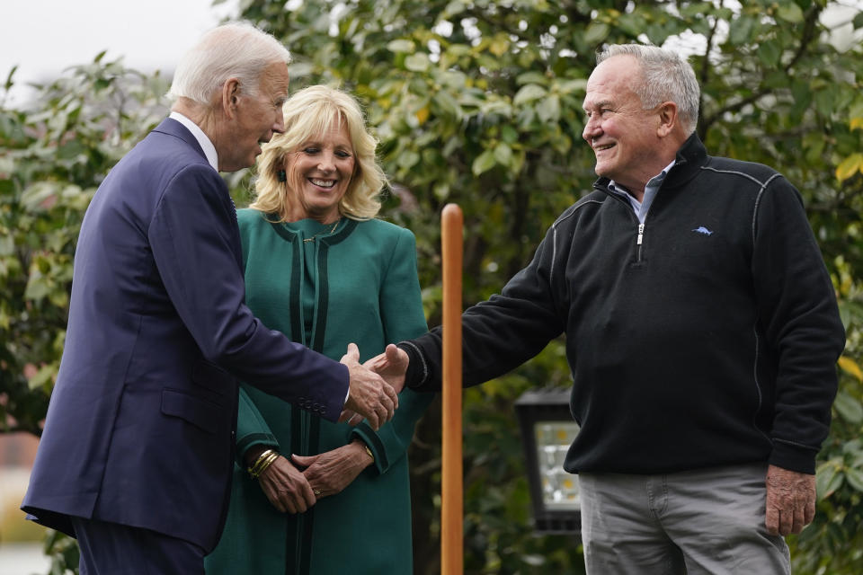 President Joe Biden shakes hands with Dale Haney, the chief White House groundskeeper, right, during a tree planting ceremony on the South Lawn of the White House, Monday, Oct. 24, 2022, in Washington. First lady Jill Biden looks on at center. The Bidens recognized Haney who as of this month has tended the lawns and gardens of the White House for 50 years. (AP Photo/Evan Vucci)