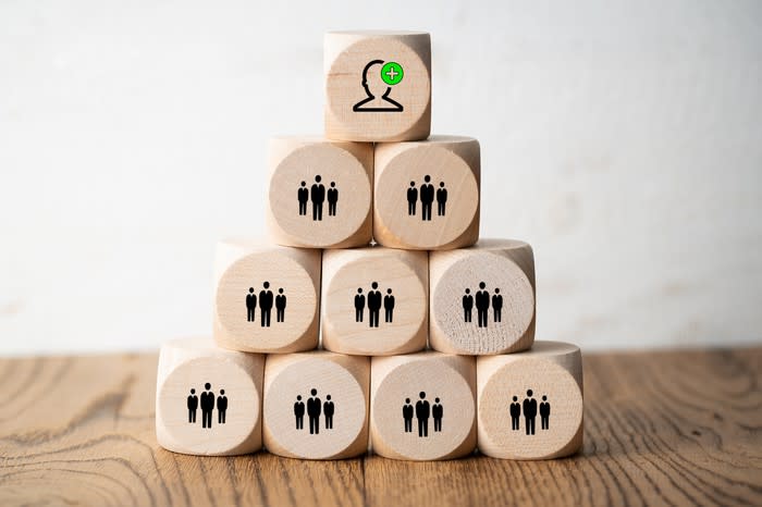 Wooden blocks stacked in a pyramid with images of business people on each block.