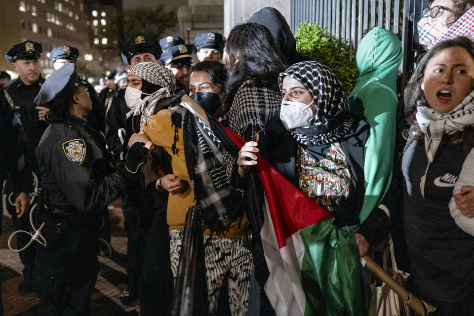 FILE - People hold their ground near a main gate at Columbia University in New York, Tuesday, April 30, 2024, as New York City police officers move to clear the area after a building was taken over by protesters earlier today. (AP Photo/Craig Ruttle, File)