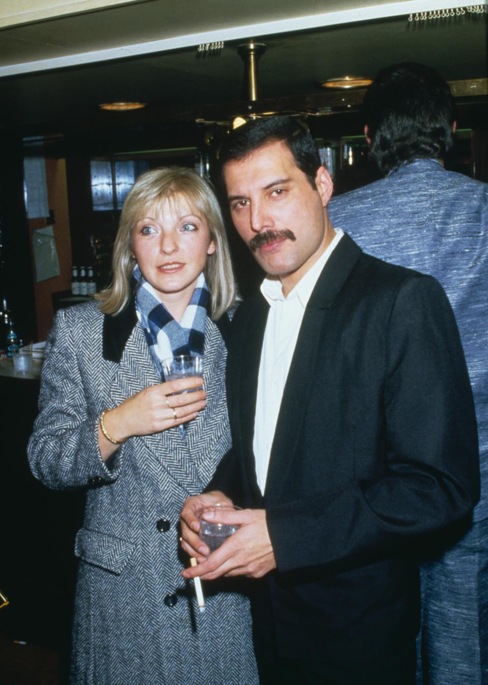 En 1973, Freddie Mercury demande Mary Austin en mariage, en lui offrant une grosse boite pour Noël. "<em>Dedans, il y avait une autre boîte, puis une autre, et ainsi de suite. C'était encore l'une de ses fantaisies amusantes. Au final, j'ai découvert une superbe bague de jade dans la plus petite boîte. En la voyant, je suis restée sans voix. Je me souviens avoir pensé</em> ‘Je sais ce qui est en train de se passer’. <em>Ce n'était absolument pas ce à quoi je m'attendais. Alors je lui ai demandé :</em> ‘A quel main dois-je la mettre ?’ <em>Et il a répondu :</em> ‘Annulaire, main gauche’. <em>Puis il a ajouté :</em> ‘Parce que... Veux-tu m'épouser ?’ <em>J'étais sous le choc. Ce n'était vraiment pas ce à quoi je m'attendais. J'ai simplement murmuré :</em> ‘Oui’<em>"</em>, se souvient-elle lors d’une interview accordée au Daily Mail en 2013. Si elle accepte, leur union ne sera finalement jamais célébrée, en partie à cause d’une infidélité du chanteur avec un cadre du label Elektra Records. <em>(Photo by Dave Hogan/Getty Images)</em>