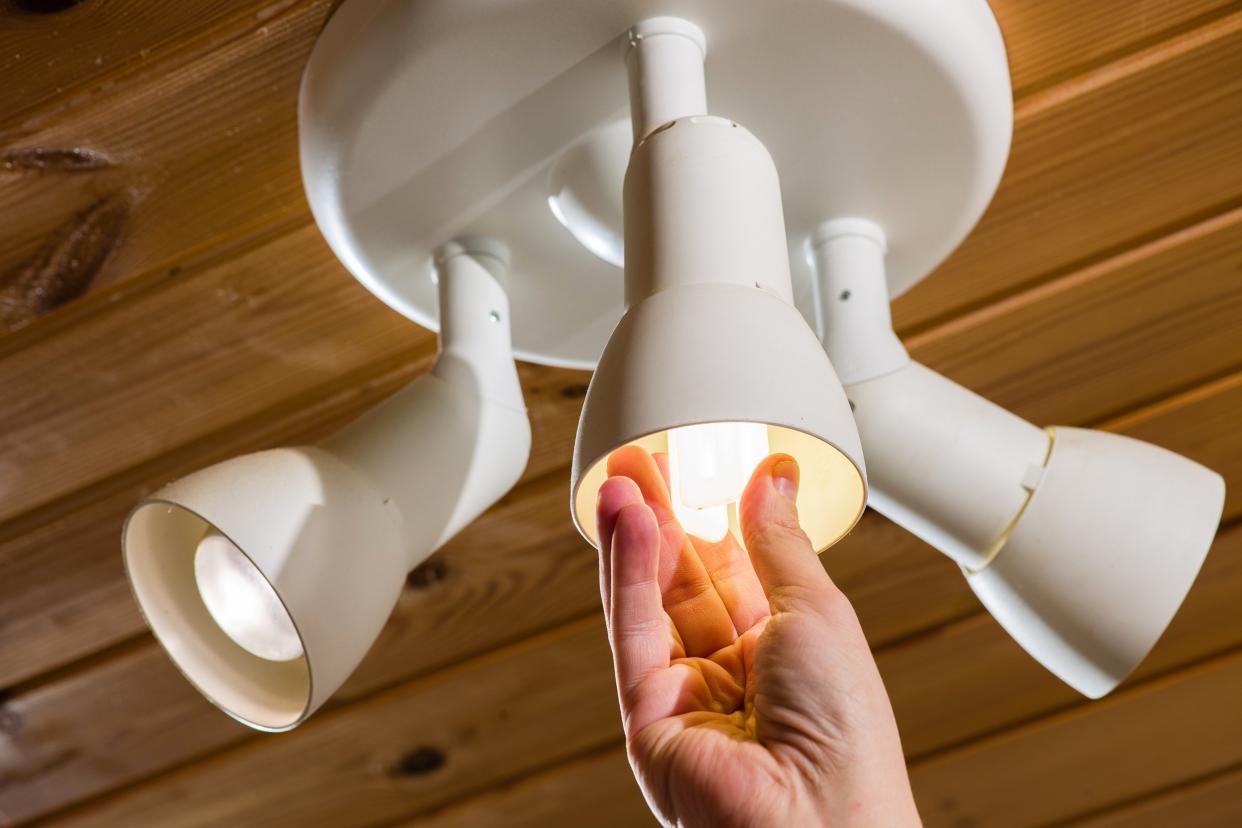 man's hand changes an electric light bulb