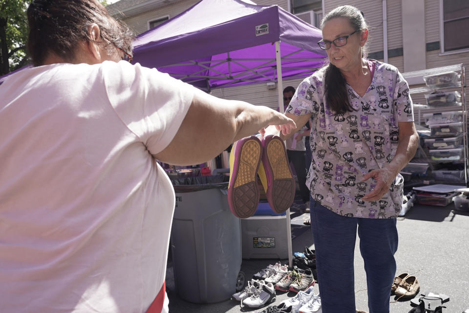 Karry Fowler, right, hands a pair of shoes to a homeless person at ShowUp Sac in Sacramento, Calif., Tuesday, Aug. 9, 2022. ShowUp Sac is a nonprofit that provides food, clothing and showers to people experiencing homelessness. Sacramento County had more than 9,200 people experiencing homelessness during this year's annual count, conducted in February. (AP Photo/Rich Pedroncelli)