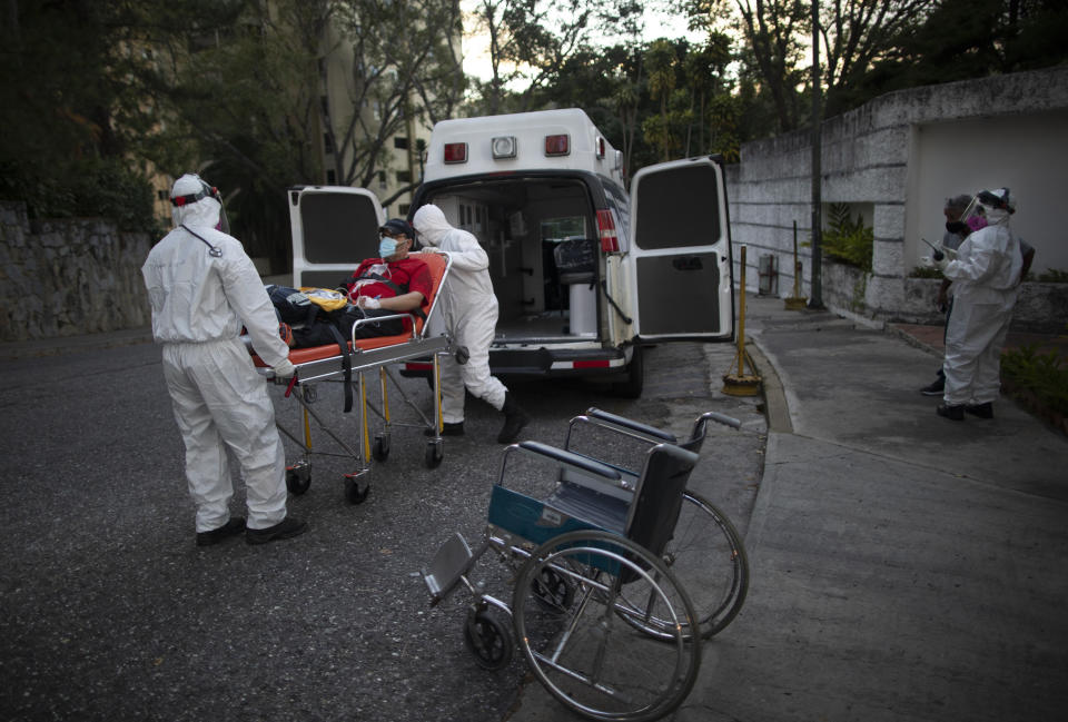 Angels of the Road volunteer paramedics transfer a person suspected of having COVID-19 into their one ambulance, in Caracas, Venezuela, Thursday, Feb. 11, 2021. Each day brings on average three to four calls, and the new coronavirus pandemic means that at least one of those is a request to take a patient with trouble breathing to a hospital. (AP Photo/Ariana Cubillos)