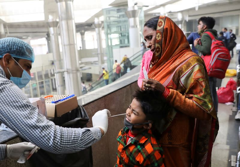 A healthcare worker collects a coronavirus disease (COVID-19) test swab sample from a boy at a bus terminal in New Delhi