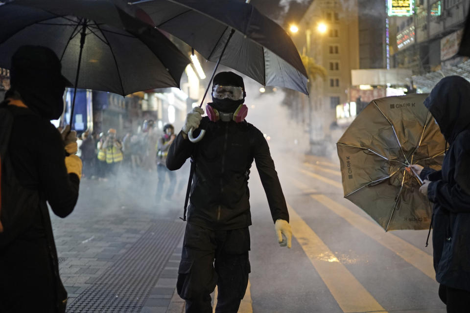 Protesters react to tear gas as police and protesters confront each other on Christmas Eve in Hong Kong, Tuesday, Dec. 24, 2019. More than six months of protests have beset the city with frequent confrontations between protesters and police. (AP Photo/Kin Cheung)