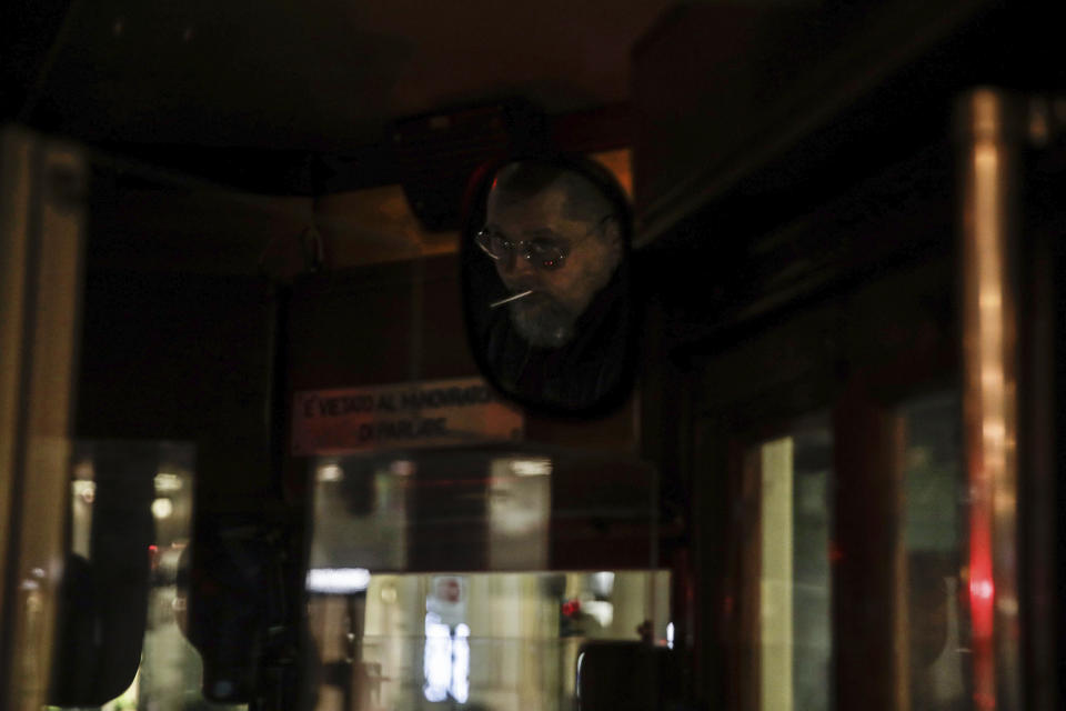 A streetcar driver is reflected in a mirror, top right, as he drives around Milan, northern Italy, early Sunday, Oct. 25, 2020. Since the 11 p.m.-5 a.m. curfew took effect last Thursday, people can only move around during those hours for reasons of work, health or necessity. (AP Photo/Luca Bruno)