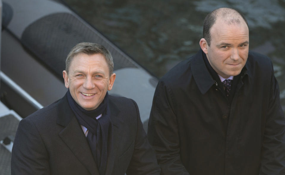 FILE - In this Tuesday, Dec. 16, 2014 file photo, actors Daniel Craig, left, and Rory Kinnear smile for photographers as they film a scene for the new James Bond film, Spectre, in London. 007 star Daniel Craig and the film's other luminaries will be at the October world premiere of the new James Bond film "Spectre", and Palace officials said Wednesday Sept. 16, 2015, they will be joined on the red carpet by Prince William and his wife Kate and Prince Harry. (AP Photo/Alastair Grant, File)