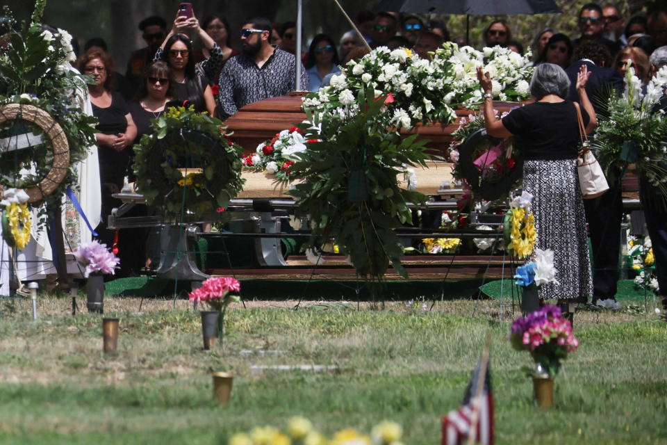 A woman raises her hands by the caskets of Irma Garcia, one of the victims of the Robb Elementary school mass shooting, and her husband Joe Garcia who died suddenly two days later, at their burial site in Hillcrest Memorial Cemetery in Uvalde, Texas, U.S., June 1, 2022. REUTERS/Shannon Stapleton     TPX IMAGES OF THE DAY