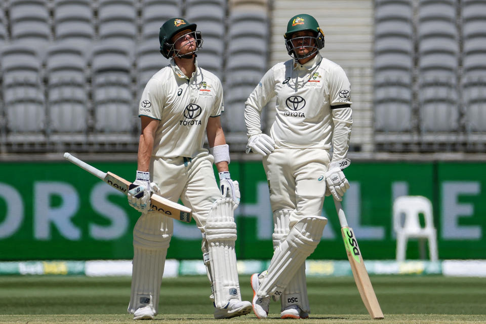 Steve Smith walks off as Usman Khawaja stands there.