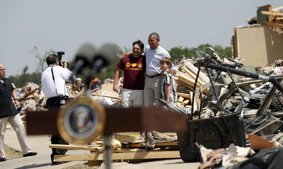 Amid the wreckage, U.S. President Barack Obama poses for a photo as he visits the tornado devastated town of Vilonia, Arkansas May 7, 2014. In the foreground is the lectern from which he made remarks. The tornadoes were part of a storm system that blew through the Southern and Midwestern United States earlier this week, killing at least 35 people, including 15 in Arkansas. Obama has already declared a major disaster in Arkansas and ordered federal aid to supplement state and local recovery efforts. (REUTERS/Kevin Lamarque)