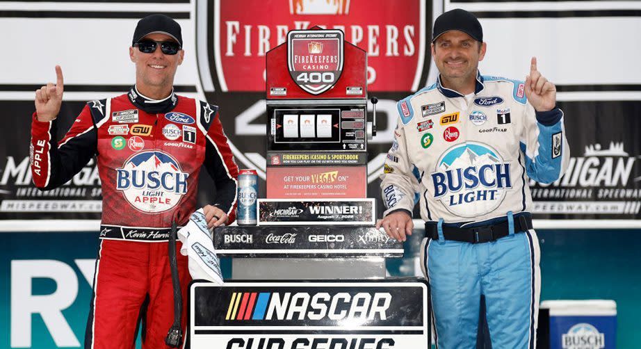 Kevin Harvick and Rodney Childers make the No. 1 sign while standing next to Michigan winner trophy
