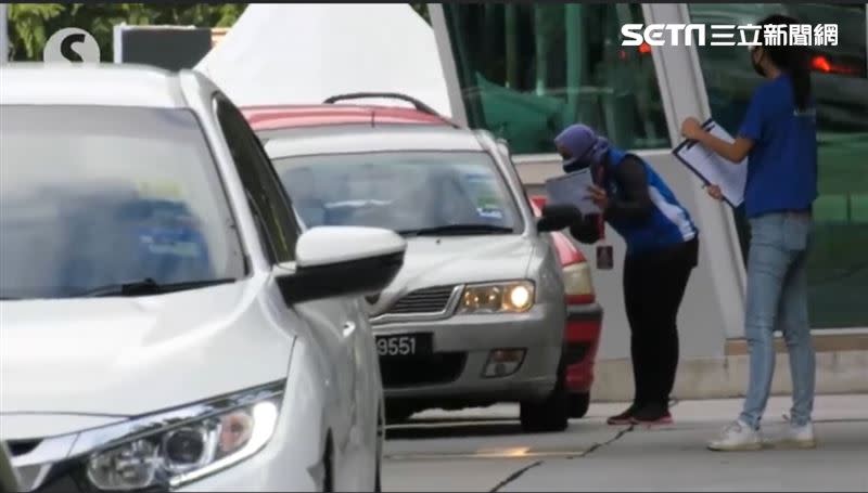 為確保接種順暢工作人員會先核對資料，民眾只需要搖下車窗。(圖/取自The Star)