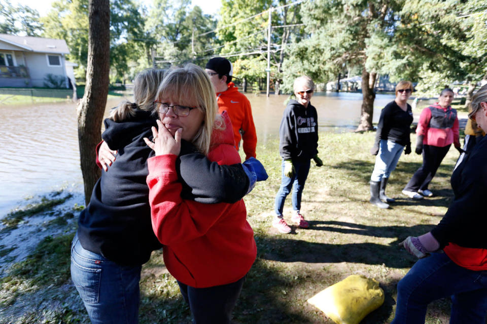 <p>Lorri Mehmen, center, hugs volunteer Doreen Steil, left, her son’s former kindergarten teacher, outside her sons home as volunteers help remove sandbags from around her son’s house on Longview Street as flood cleanup begins in the North Cedar neighborhood Monday, Sept. 26, 2016, in Cedar Falls, Iowa. (Matthew Putney/The Waterloo Courier via AP)</p>