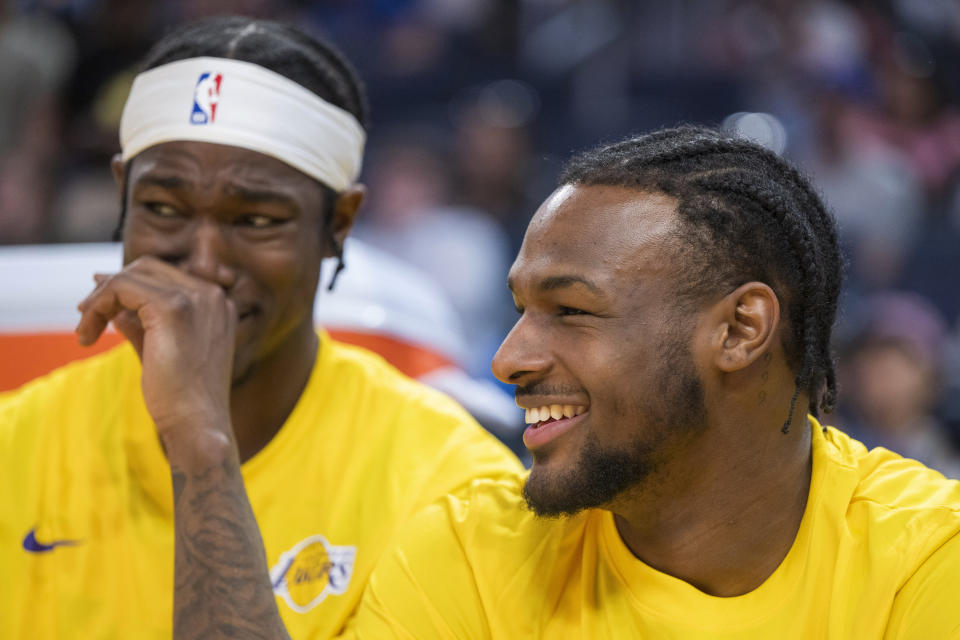 Los Angeles Lakers guard Bronny James, right, laughs with teammates while sitting on the bench during the second half of an NBA summer league basketball game against the Golden State Warriors in San Francisco, Sunday, July 7, 2024. (AP Photo/Nic Coury)