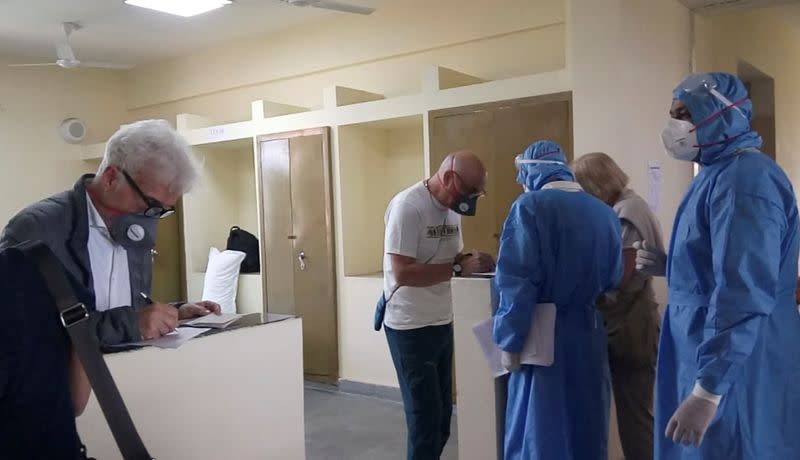 Italian tourists fill up forms next to medical staff members at an Indo-Tibetan Border Police (ITBP) quarantine facility in Chhawla on the outskirts of New Delhi