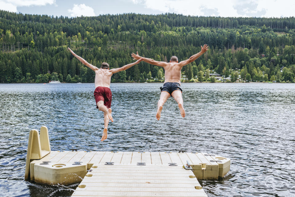 Germany, Lake Titisee, two men jumping into lake from a jetty