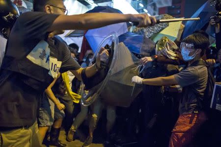 A riot police officer holds a baton as he confronts pro-democracy protesters on a blocked road at Mongkok shopping district in Hong Kong October 17, 2014.REUTERS/Tyrone Siu