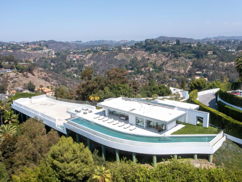 an aerial view of white mansion The One Bel Air, surrounded by hills and trees