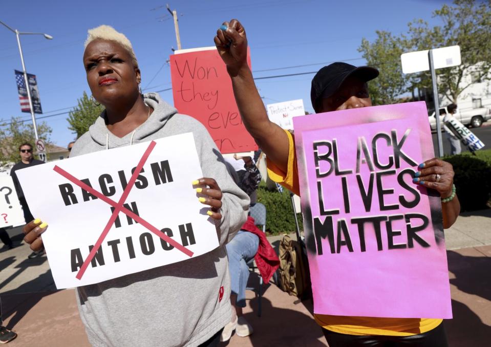 Two people hold signs while protesting.