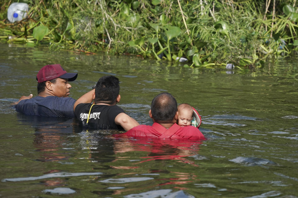 Migrants cross the Rio Grande river, one of them with a child in his arms, seen from Matamoros, Mexico, Wednesday, May 10, 2023. The U.S. on May 11 will begin denying asylum to migrants who show up at the U.S.-Mexico border without first applying online or seeking protection in a country they passed through, according to a new rule released on May 10. (AP Photo/Fernando Llano)