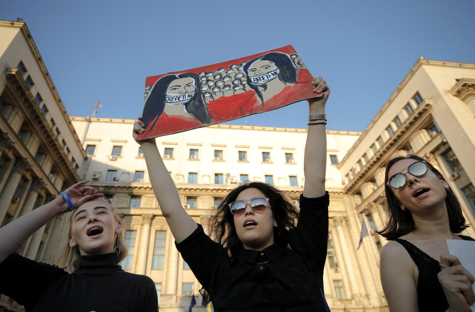 A protester holds a placard depicting women their mouth covered by tape that reads "Believe us" during a rally in memory of a 15 year-old girl, raped and killed in southern Romania, after police took 19 hours from the moment she called the country's emergency hotline to intervene, in Bucharest, Romania, Sunday, July 28, 2019. More than one hundred people took part Sunday evening in a protest against the way police handled the case. (AP Photo/Vadim Ghirda)