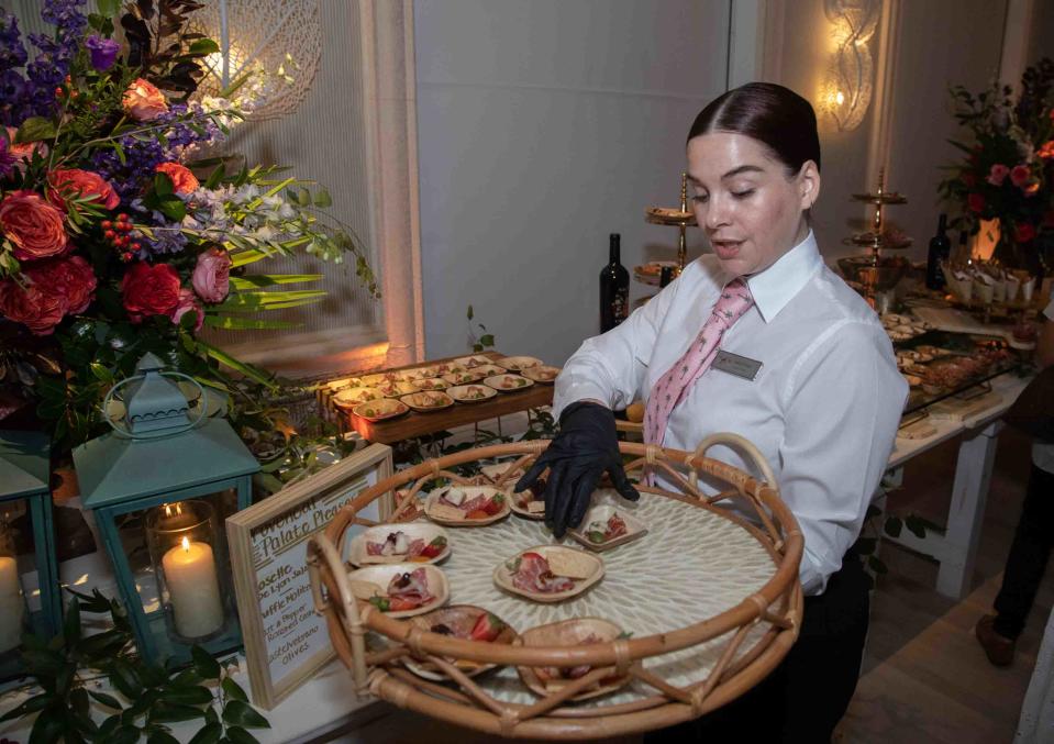 A server passes out samples of charcuterie boards created by the company Boarderie in the ballroom at The Colony Hotel.