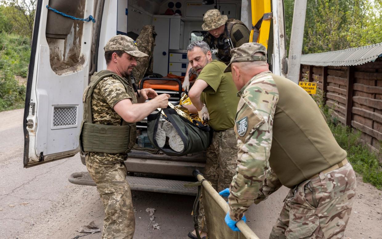 Soldiers evacuate a wounded comrade from the front line in Ukraine
