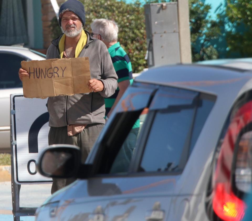 A panhandler holding a sign that says "hungry" positions himself on Oakridge Boulevard near State Road A1A in Daytona Beach in this file photo. In the past few years, cities in Volusia County have enacted ordinances targeting panhandlers and solicitors. DeBary's, out of concern for Constitutional rights, focuses on "street harassment" and "traffic and pedestrian safety."