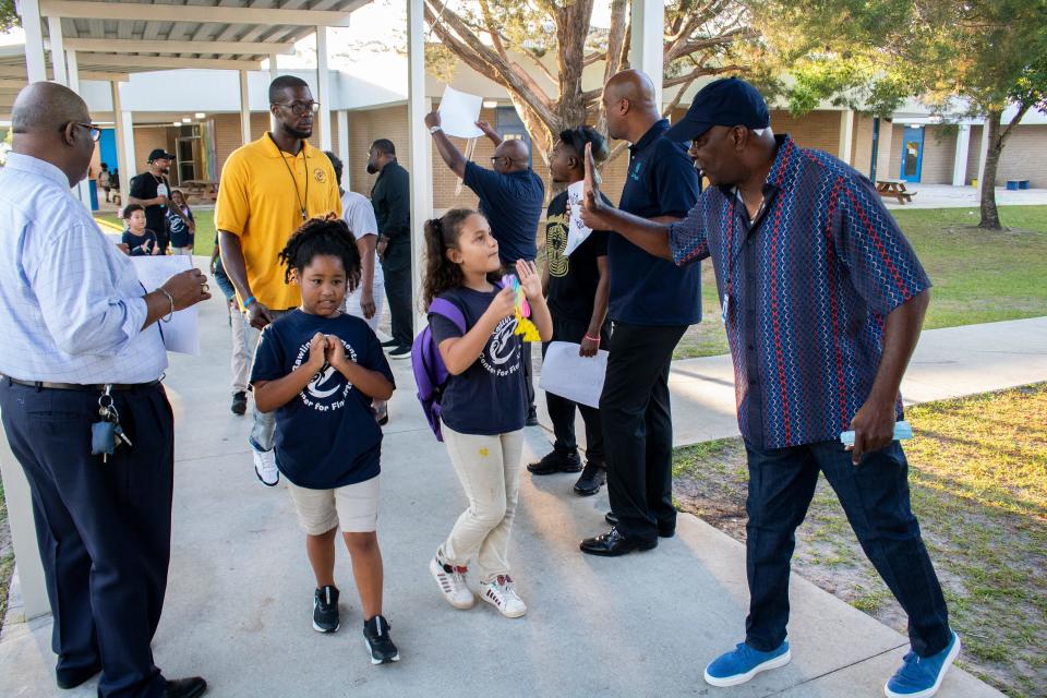 Claude Bonds, right, an assistant pastor at Mount Carmel Baptist Church, high fives a student Thursday at Rawlings Elementary School during the father cheering event organized by the Fatherhood Initiative of Gainesville For All held to encourage students before they took the math part of the Florida Student Assessment end-of-year test.