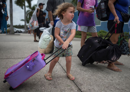 Chloe Rosenberger, a three-year old from Cape Coral, Florida, carries her belongings while following her brother and mother into a shelter ahead of the downfall of Hurricane Irma in Estero, Florida, U.S. September 9, 2017. REUTERS/Adrees Latif