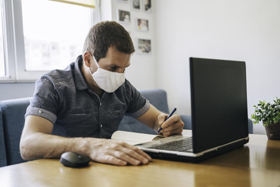 Businessman working on laptop from home wearing protective mask. COVID- 19. Coronavirus epidemic.