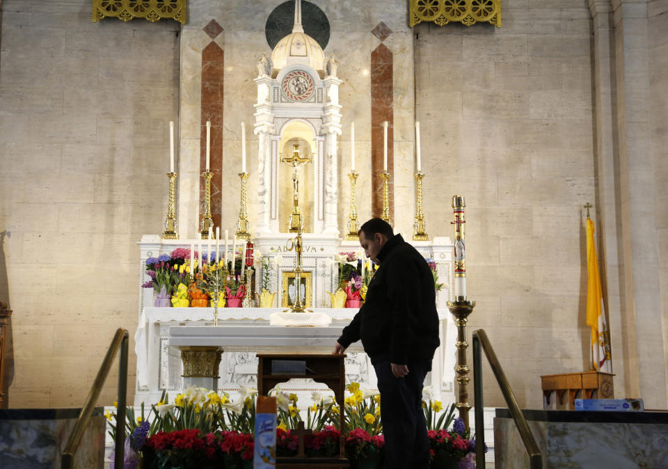 In this April 19, 2020, photo, the Rev. Joseph Dutan, 32, stands near the altar as he prepares for a virtual holy hour livestreamed after Sunday Mass at St. Brigid Church in the Brooklyn borough of New York. (AP Photo/Jessie Wardarski)