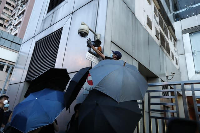 A protester spray-paints the CCTV camera outside the Chinese Liaison Office 