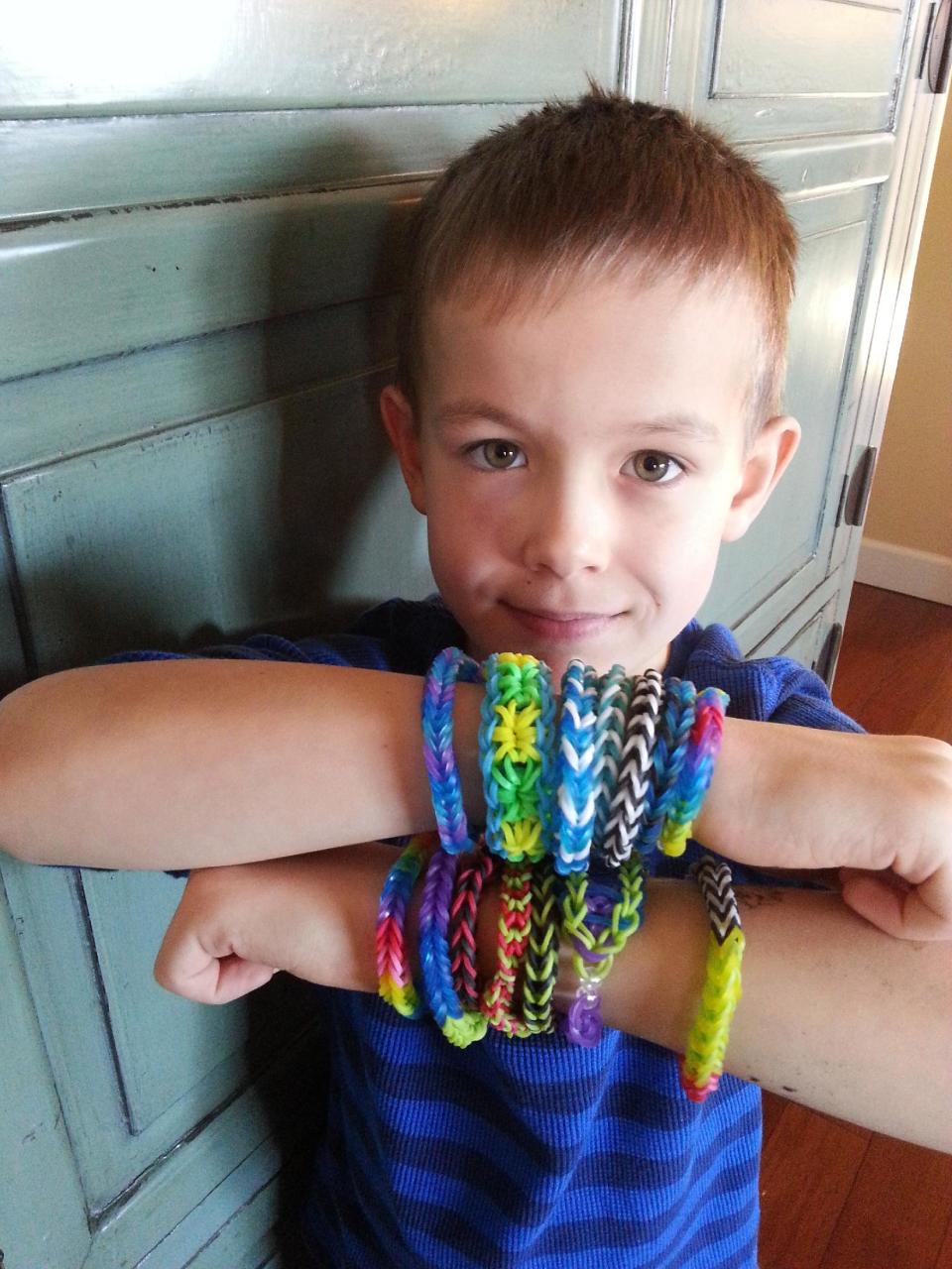 In this Dec. 7, 2013 photo, Cooper Volkman, 8 years old, wears loom band bracelets that he made in Ridgefield, Wash. When kids collected Silly Bands, parents groaned. But the current craze for kids, Rainbow Loom bands and their many knockoffs, is surprising parents and child development experts. (AP Photo/Lori L. Volkman)