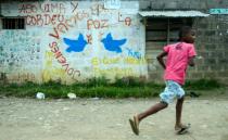 A boy runs past a mural reading, "Youngsters let's go for peace" in Apartado, Antioquia department, Colombia on June 13, 2016