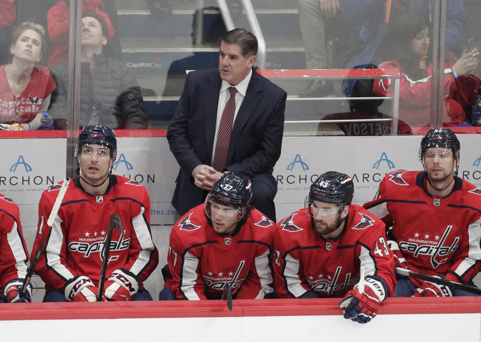 Washington Capitals coach Peter Laviolette stands behind player during the second period of the team's NHL hockey game against the Toronto Maple Leafs, Monday, Feb. 28, 2022, in Washington. (AP Photo/Luis M. Alvarez)