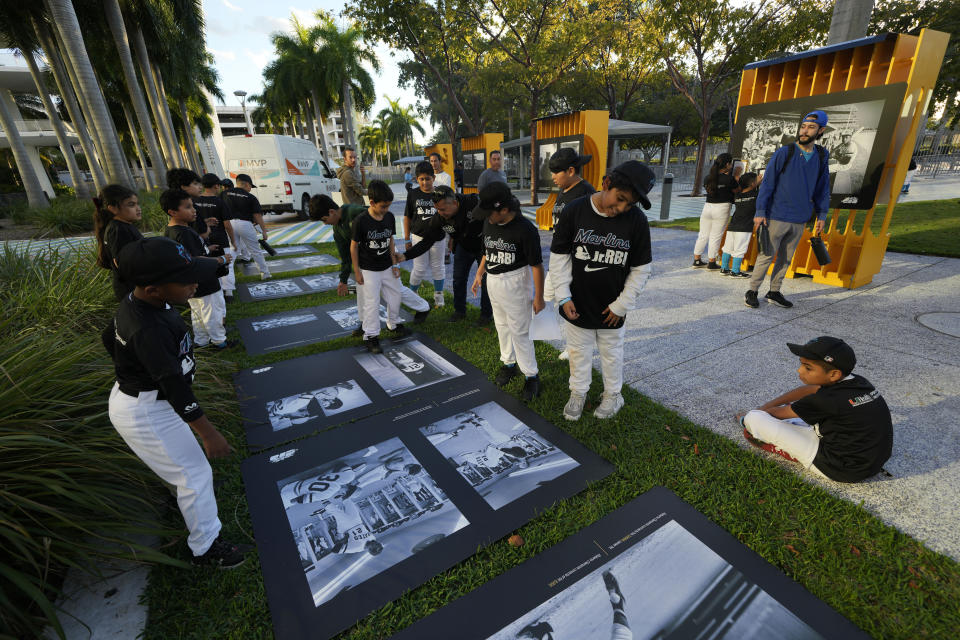 Un grupo de niños observan las imágenes de la exhibición sobre la carrera del fallecido beisbolista Roberto Clemente, en el estadio de los Marlins de Miami, el miércoles 31 de enero de 2024. (AP Foto/Rebecca Blackwell)