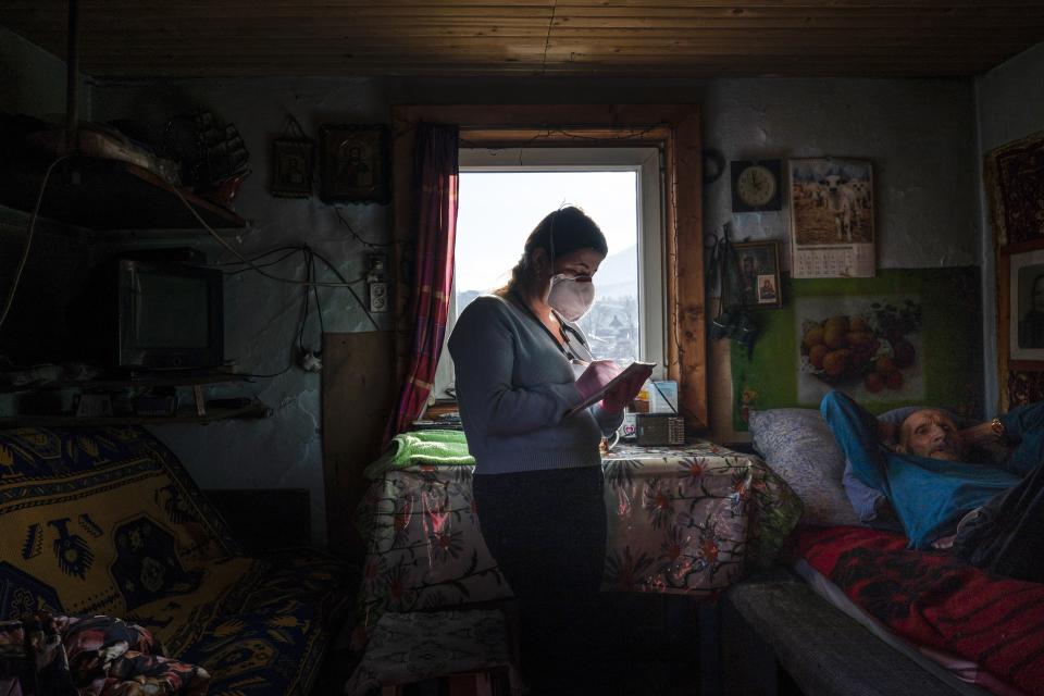 Dr. Viktoria Mahnych, wearing face mask against coronavirus, writes down in her notebook while visiting an elderly patient with COVID-19 in Iltsi village, Ivano-Frankivsk region of Western Ukraine, Wednesday, Jan. 6, 2021. Ukraine is struggling to contain the coronavirus pandemic that has inundated its overburdened medical system, as Dr. Viktoria Mahnych goes door to door providing much needed help to patients. (AP Photo/Evgeniy Maloletka)